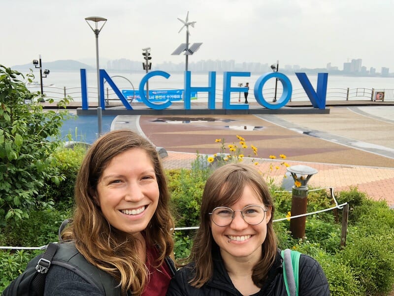 Two women taking a selfie in front of the Incheon city sign
