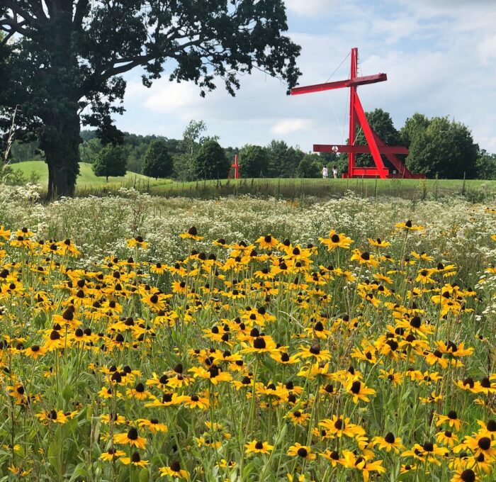 Mark di Suvero Mother Peace Sculpture behind yellow flowers at Storm King Guide