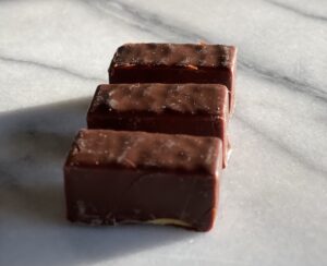 3 pieces of ptasie mleczko candies from Poland sitting on a marble surface