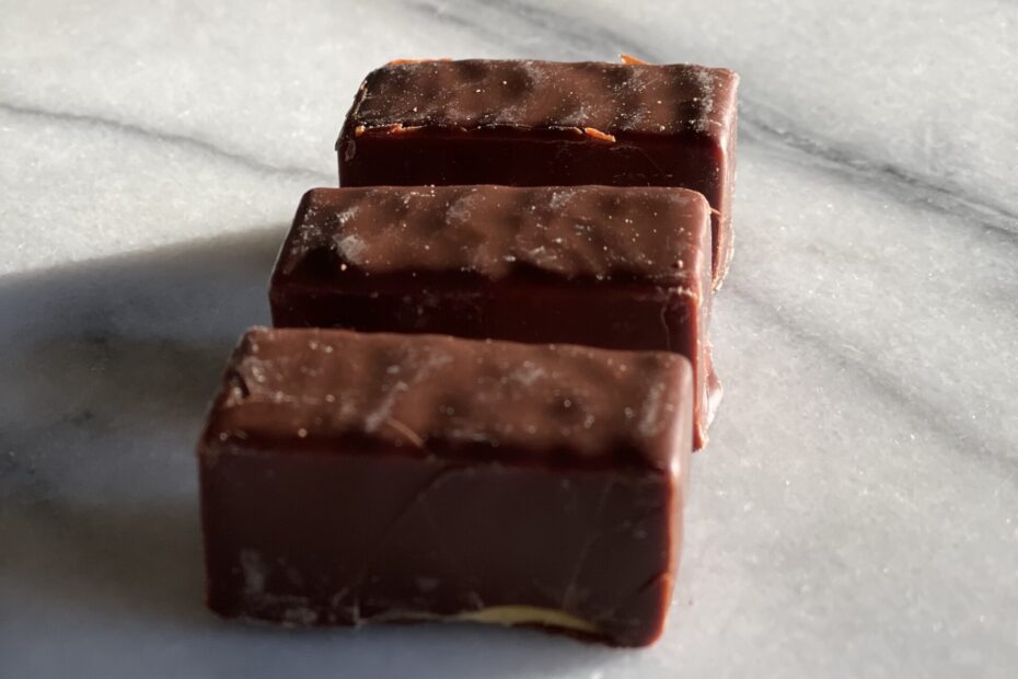 3 pieces of ptasie mleczko candies from Poland sitting on a marble surface