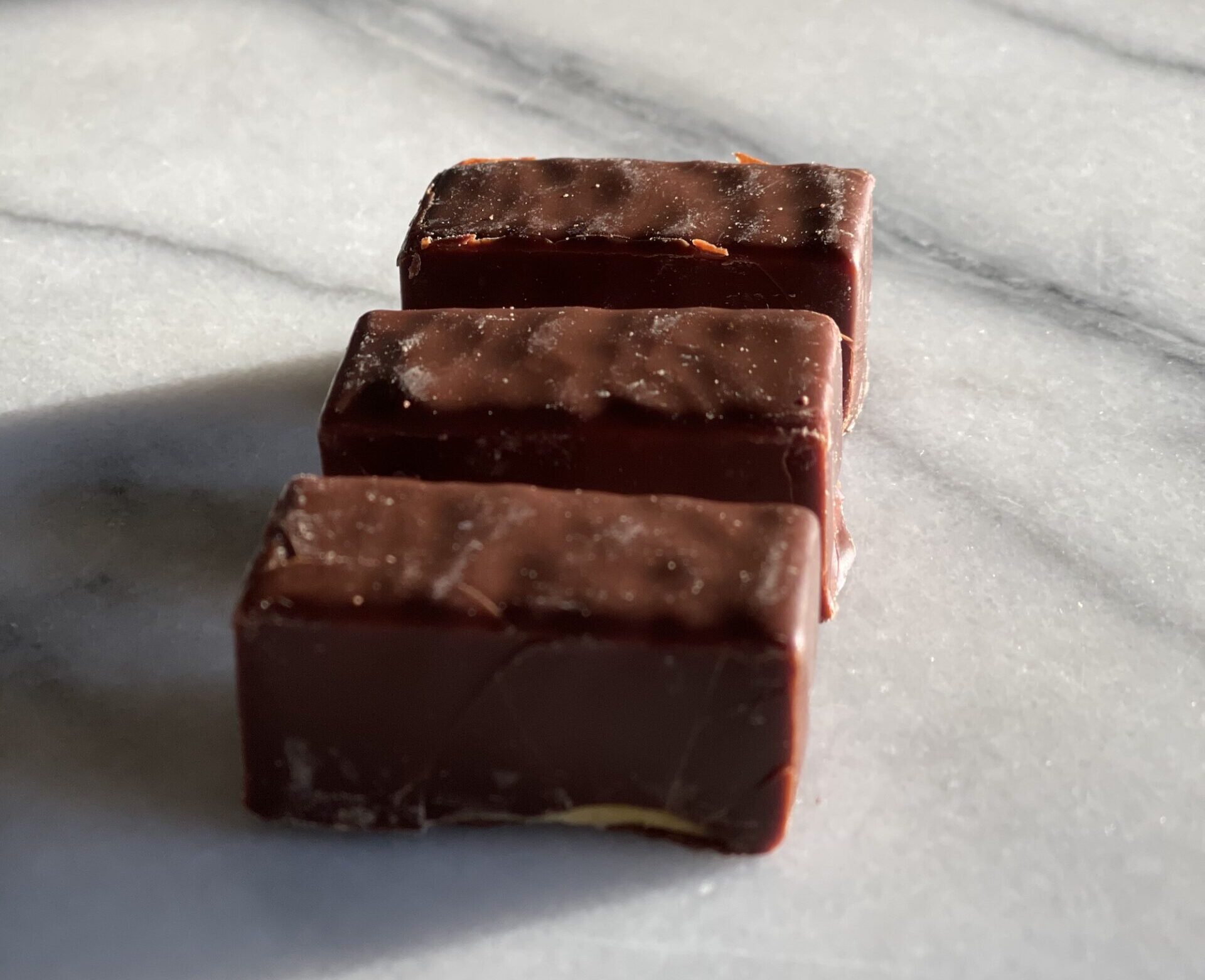 3 pieces of ptasie mleczko candies from Poland sitting on a marble surface