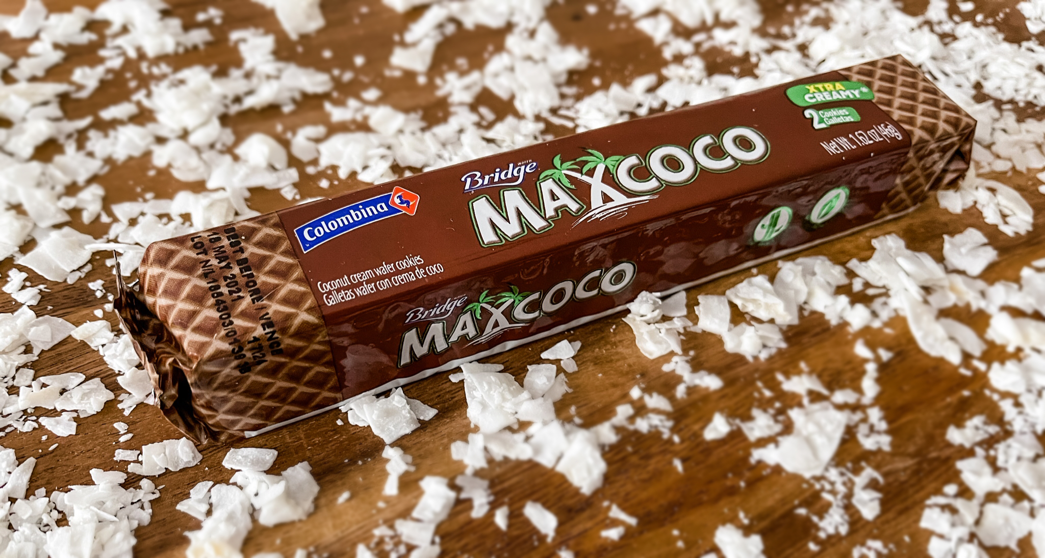 Max Coco Colombian wafer cookie bar on a table surrounded by coconut chips