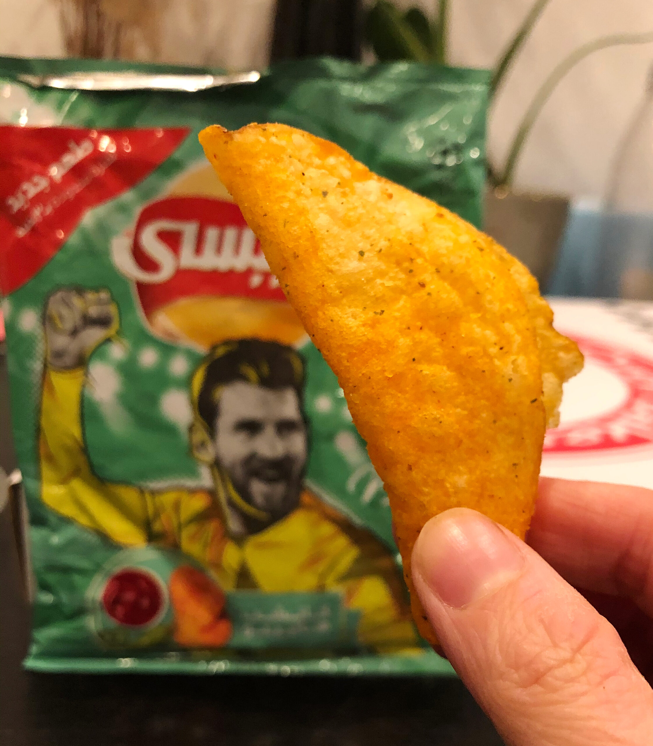 Jalapeno Ketchup Flavored Potato Chips with one chip held up in front a bag
