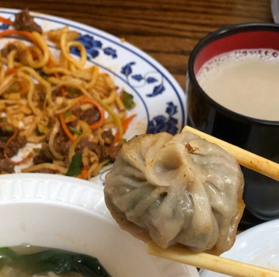 Chive momo up close being held by a chopstick