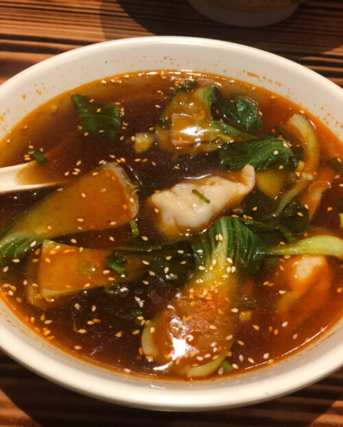 Close up photo of Dumpling Soup from Khampa Kitchen with spicy broth, bok choy and dumplings.