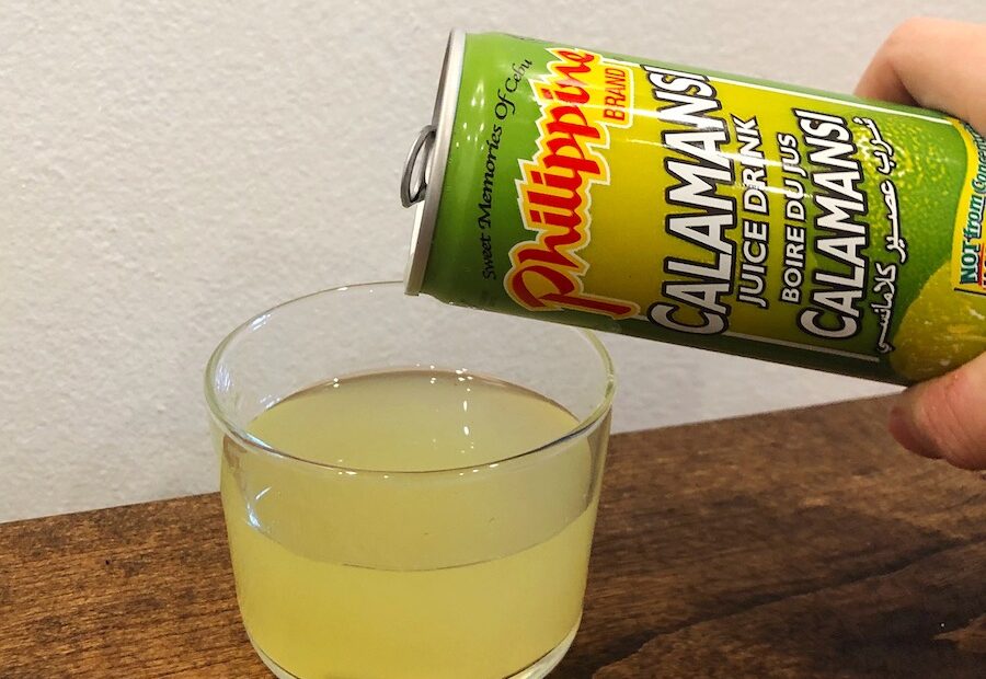 Calamansi Juice Drink being poured into a small glass on a wooden surface