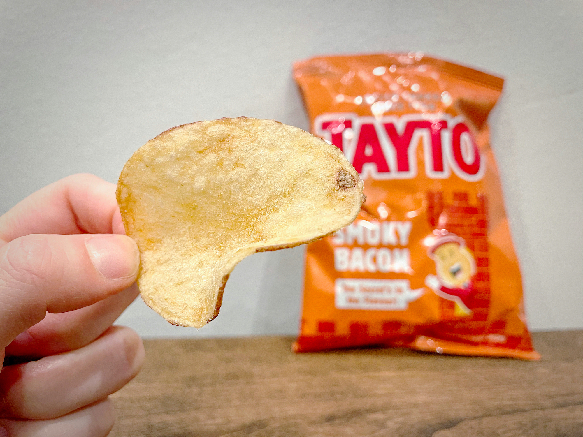 Close-up of a Tayto Smoky Bacon Crisps with a bag blurred in the background