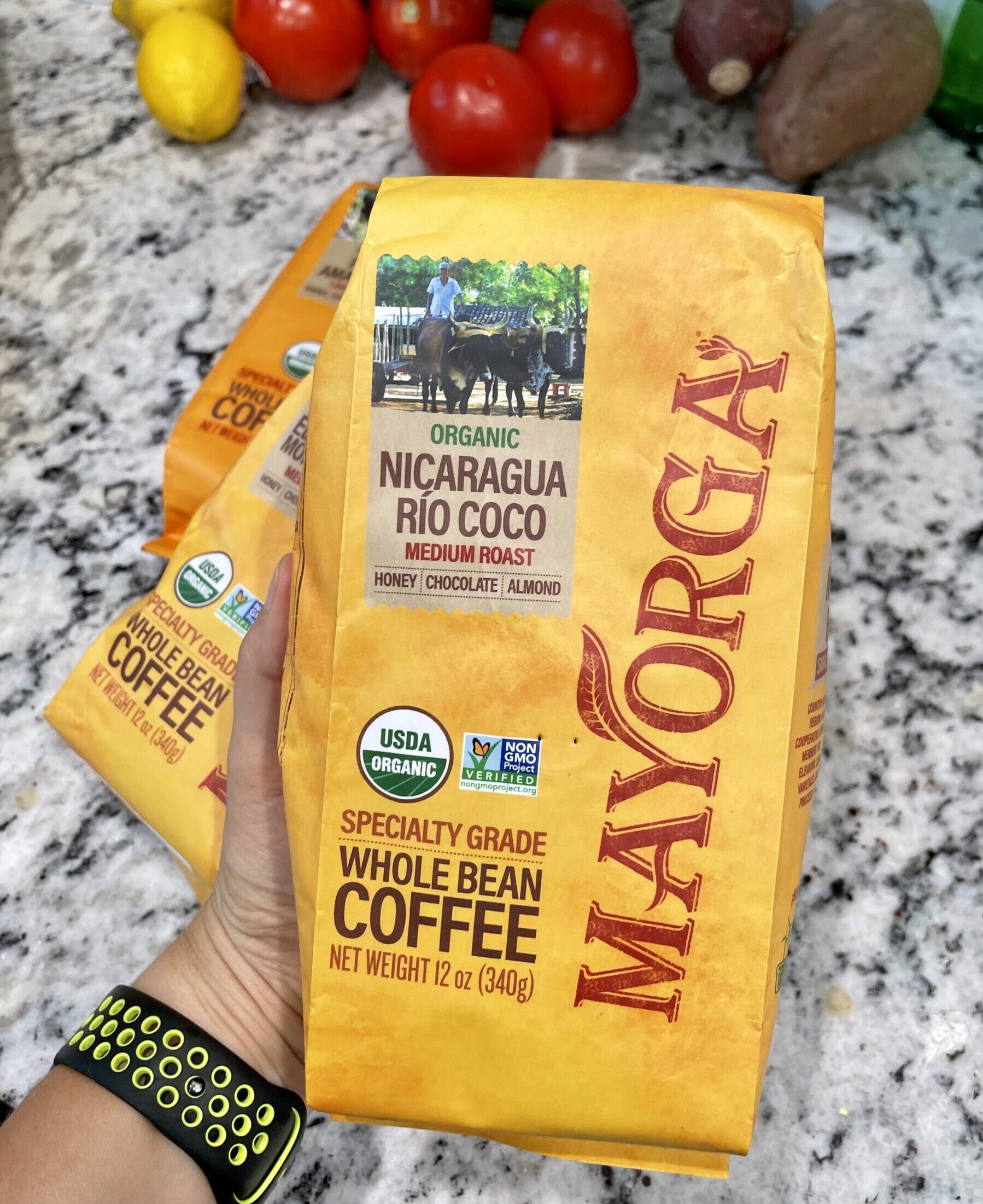 Mayorga Coffee Bag in a Hand with vegetables in the background